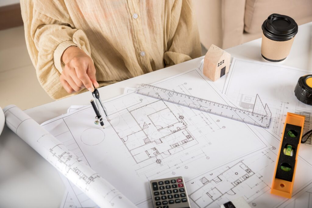 Architect drawing with divider compass on house plan blueprint paper